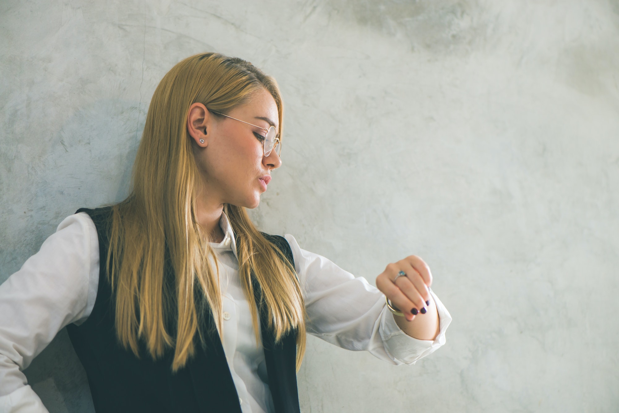 Business and time management concept. Young businesswoman looking at wrist watch. Time is money