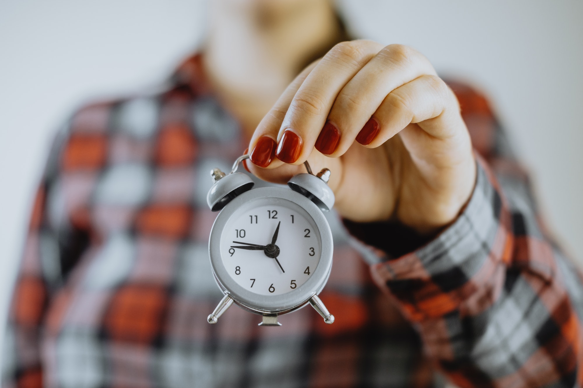 Time management. Small alarm clock in female hands